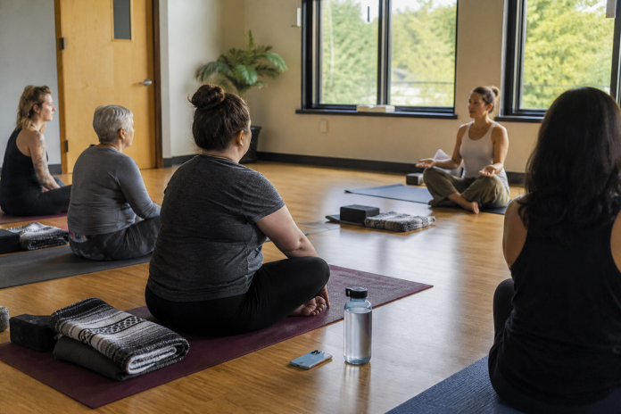 Small trauma-informed yoga class seated on mats in a bright community-centre room