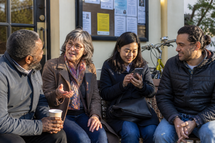 Kinds of spirituality: community outside a hall Four people talking on a bench outside a community hall after an event